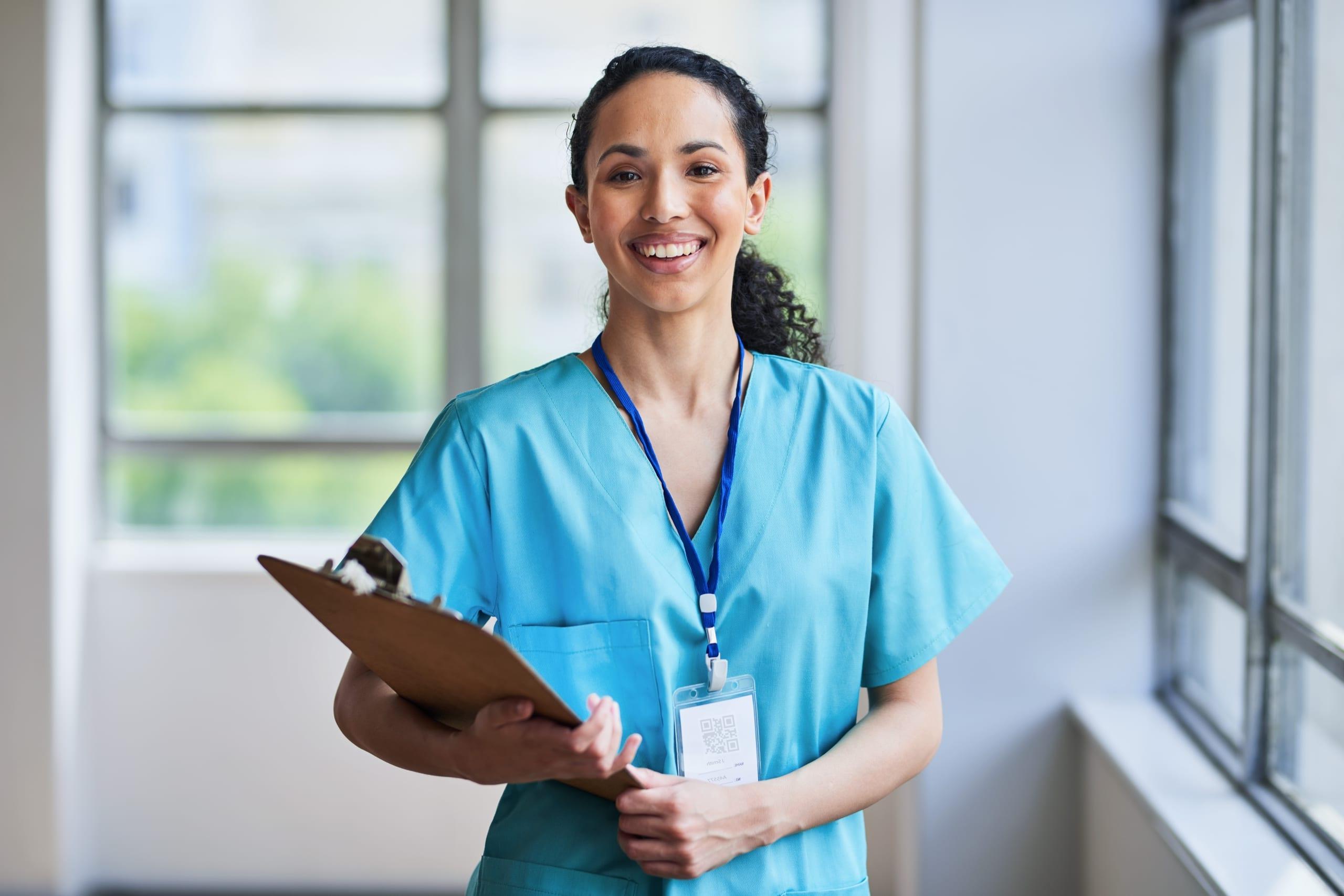 Smiling medical professional in scrubs with a clipboard